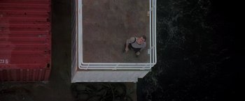 Movie still from “Die Hard with a Vengeance” (1995), directed by John McTiernan – A man is sitting on the ground looking up at the sky; Extreme Wide shot, Overhead angle