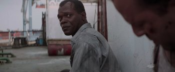 Movie still from “Die Hard with a Vengeance” (1995), directed by John McTiernan – A black man with a beard is leaning against a wall; Close Up shot, Over the shoulder angle
