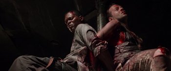 Movie still from “Die Hard with a Vengeance” (1995), directed by John McTiernan – Two men are covered in blood in a dark room; Medium shot, Low angle