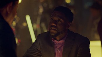 Movie still from “Die Hart” (2023), directed by Eric Appel – A man wearing a suit and a pink shirt; Close Up shot, Over the shoulder angle