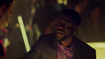 Movie still from “Die Hart” (2023), directed by Eric Appel – A person wearing a suit and tie; Close Up shot, Over the shoulder angle