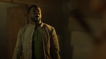 Movie still from “Die Hart” (2023), directed by Eric Appel – A man standing in the dark with his mouth open; Medium shot, Low angle