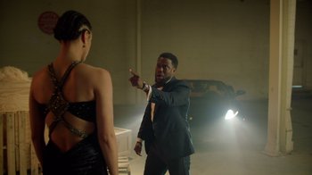 Movie still from “Die Hart” (2023), directed by Eric Appel – A man and a woman are standing in a dark room; Medium shot, Over the shoulder angle