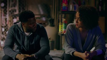 Movie still from “Die Hart” (2023), directed by Eric Appel – A man and a woman sitting next to each other on a couch; Medium shot, Over the shoulder angle