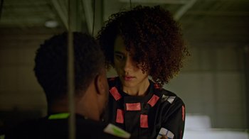 Movie still from “Die Hart” (2023), directed by Eric Appel – A woman with curly hair is talking to a man; Close Up shot, Over the shoulder angle