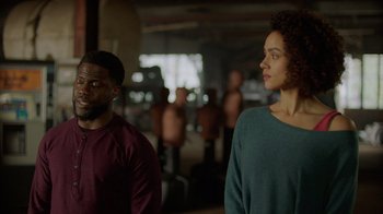 Movie still from “Die Hart” (2023), directed by Eric Appel – A man and a woman standing next to each other in a room; Medium shot, Over the shoulder angle