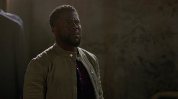 Movie still from “Die Hart” (2023), directed by Eric Appel – A black man in a brown jacket looking up; Close Up shot, Over the shoulder angle
