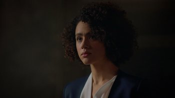Movie still from “Die Hart” (2023), directed by Eric Appel – A person with curly hair wearing a suit; Close Up shot, Low angle