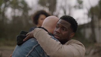 Movie still from “Die Hart” (2023), directed by Eric Appel – A man hugging another man while another man looks on; Close Up shot, Over the shoulder angle