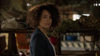 Movie still from “Die Hart” (2023), directed by Eric Appel – A woman standing in front of some plants; Close Up shot, Over the shoulder angle