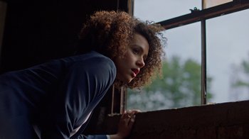 Movie still from “Die Hart” (2023), directed by Eric Appel – A woman leaning up against a window sill; Close Up shot, Low angle