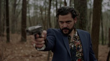 Movie still from “Die Hart” (2023), directed by Eric Appel – A man in a blue suit is holding a gun; Close Up shot, Low angle
