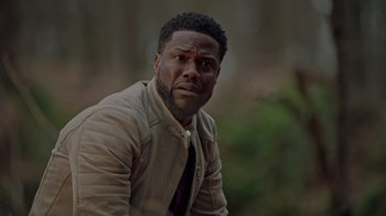 Movie still from “Die Hart” (2023), directed by Eric Appel – A person wearing a suit and tie; Close Up shot, Over the shoulder angle