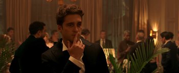 Movie still from “Die in a Gunfight” (2021), directed by Collin Schiffli – A man in a black suit and white tie smoking a cigarette; Close Up shot, Over the shoulder angle