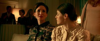 Movie still from “Die in a Gunfight” (2021), directed by Collin Schiffli – Two women sitting next to each other in front of a wall; Close Up shot, Over the shoulder angle