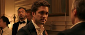 Movie still from “Die in a Gunfight” (2021), directed by Collin Schiffli – A man in a black suit and white tie; Close Up shot, Over the shoulder angle