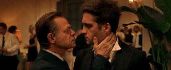 Movie still from “Die in a Gunfight” (2021), directed by Collin Schiffli – Two men in suits touching each other's neck; Close Up shot, Over the shoulder angle