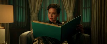 Movie still from “Die in a Gunfight” (2021), directed by Collin Schiffli – A woman sitting in a chair reading a book; Close Up shot, Over the shoulder angle