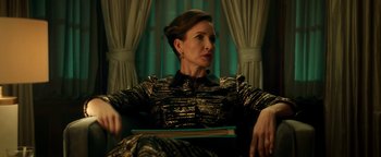 Movie still from “Die in a Gunfight” (2021), directed by Collin Schiffli – A woman sitting in a chair with a book in her lap; Medium shot, Low angle