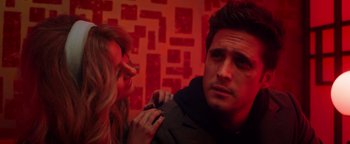 Movie still from “Die in a Gunfight” (2021), directed by Collin Schiffli – A woman standing next to a man in a red room; Close Up shot, Over the shoulder angle