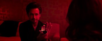 Movie still from “Die in a Gunfight” (2021), directed by Collin Schiffli – A man holding up a cell phone in front of a woman; Close Up shot, Over the shoulder angle