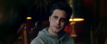 Movie still from “Die in a Gunfight” (2021), directed by Collin Schiffli – A young man with a bruised eye sitting in a chair; Close Up shot, Low angle