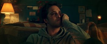 Movie still from “Die in a Gunfight” (2021), directed by Collin Schiffli – A man sitting on a couch with his hand on his face; Close Up shot, Low angle