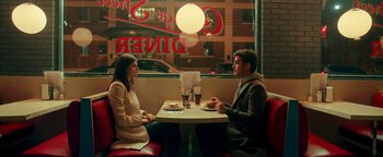 Movie still from “Die in a Gunfight” (2021), directed by Collin Schiffli – A man and a woman sitting at a table in a restaurant; Medium shot, High angle