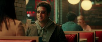 Movie still from “Die in a Gunfight” (2021), directed by Collin Schiffli – A man sitting at a table in front of a laptop; Close Up shot, Over the shoulder angle