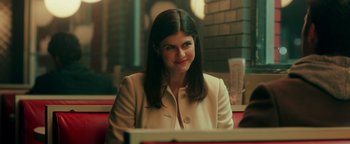 Movie still from “Die in a Gunfight” (2021), directed by Collin Schiffli – A woman sitting at a table in front of a laptop; Close Up shot, Over the shoulder angle