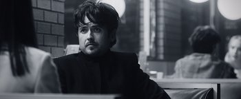 Movie still from “Die in a Gunfight” (2021), directed by Collin Schiffli – Black and white photograph of a man in a black suit; Close Up shot, Over the shoulder angle