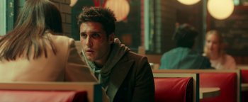 Movie still from “Die in a Gunfight” (2021), directed by Collin Schiffli – A man sitting at a table in front of a window; Close Up shot, Over the shoulder angle