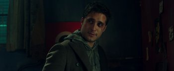 Movie still from “Die in a Gunfight” (2021), directed by Collin Schiffli – A man in a jacket and a hoodie is smiling for the camera; Close Up shot, Over the shoulder angle