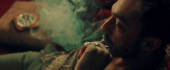 Movie still from “Die in a Gunfight” (2021), directed by Collin Schiffli – A man smoking a cigarette while lying down; Close Up shot, High angle