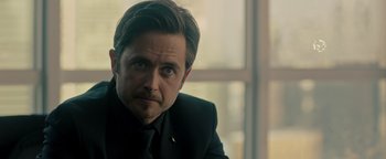 Movie still from “Die in a Gunfight” (2021), directed by Collin Schiffli – A person wearing a suit and tie; Close Up shot, Over the shoulder angle