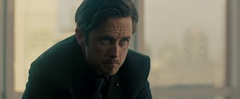 Movie still from “Die in a Gunfight” (2021), directed by Collin Schiffli – A person wearing a suit and tie; Close Up shot, Over the shoulder angle