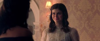 Movie still from “Die in a Gunfight” (2021), directed by Collin Schiffli – A woman standing in front of a lamp in a room; Close Up shot, Over the shoulder angle