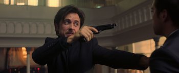 Movie still from “Die in a Gunfight” (2021), directed by Collin Schiffli – A man holding a gun in his hand; Close Up shot, Low angle