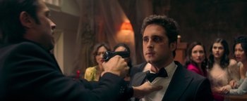 Movie still from “Die in a Gunfight” (2021), directed by Collin Schiffli – A man in a tuxedo holding a gun in his hand; Close Up shot, Over the shoulder angle