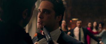 Movie still from “Die in a Gunfight” (2021), directed by Collin Schiffli – A man in a suit and tie holding a gun; Close Up shot, Over the shoulder angle
