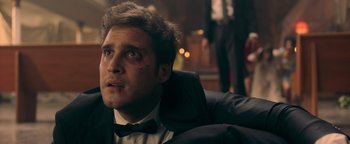 Movie still from “Die in a Gunfight” (2021), directed by Collin Schiffli – A person wearing a suit and bow tie; Close Up shot, Low angle