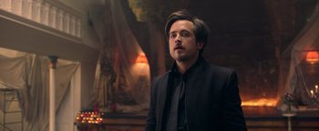 Movie still from “Die in a Gunfight” (2021), directed by Collin Schiffli – A man in a black suit and a black tie; Close Up shot, Over the shoulder angle