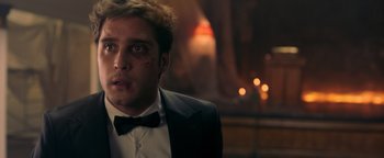 Movie still from “Die in a Gunfight” (2021), directed by Collin Schiffli – A person wearing a suit and bow tie; Close Up shot, Over the shoulder angle