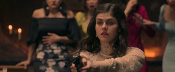 Movie still from “Die in a Gunfight” (2021), directed by Collin Schiffli – A woman holding a gun while standing in front of other women; Close Up shot, Over the shoulder angle