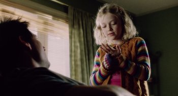Movie still from “War of the Worlds” (2005), directed by Steven Spielberg – A little girl in a colorful sweater clasps her hands; Medium shot, Over the shoulder angle