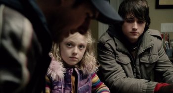 Movie still from “War of the Worlds” (2005), directed by Steven Spielberg – A young girl sitting in front of two other people; Close Up shot, Over the shoulder angle