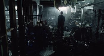 Movie still from “War of the Worlds” (2005), directed by Steven Spielberg – A man standing in a room filled with trash; Wide shot, High angle
