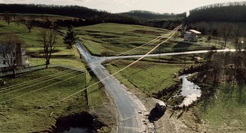 Movie still from “War of the Worlds” (2005), directed by Steven Spielberg – An aerial view of an empty road in the middle of a field; Extreme Wide shot, High angle