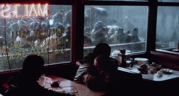 Movie still from “War of the Worlds” (2005), directed by Steven Spielberg – Two people sitting at a table in front of a window; Wide shot, High angle
