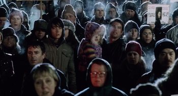 Movie still from “War of the Worlds” (2005), directed by Steven Spielberg – A group of people standing in a crowd wearing winter coats; Medium shot, High angle